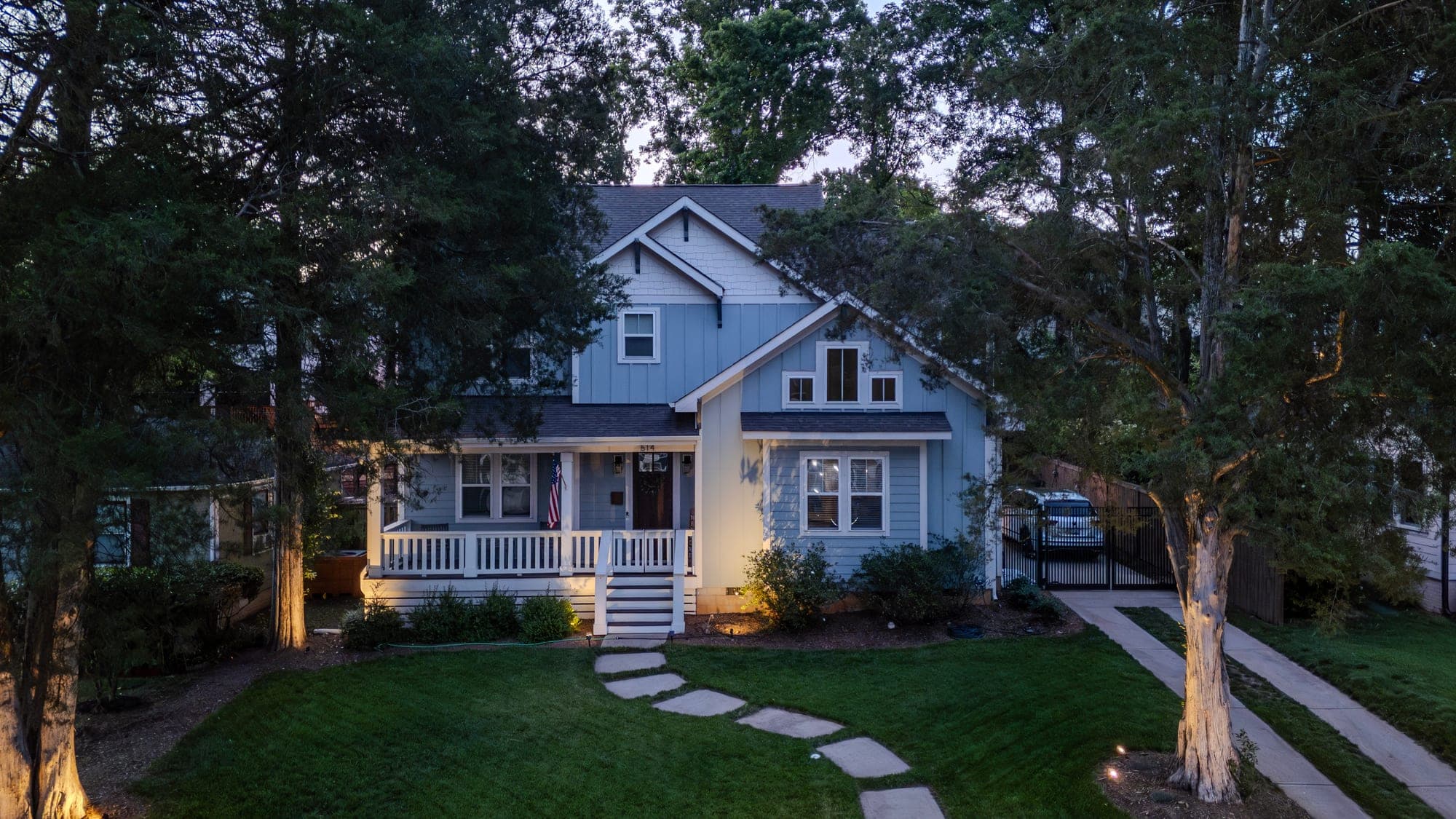 Twilight aerial of a home lit up at dusk with warm exterior lighting